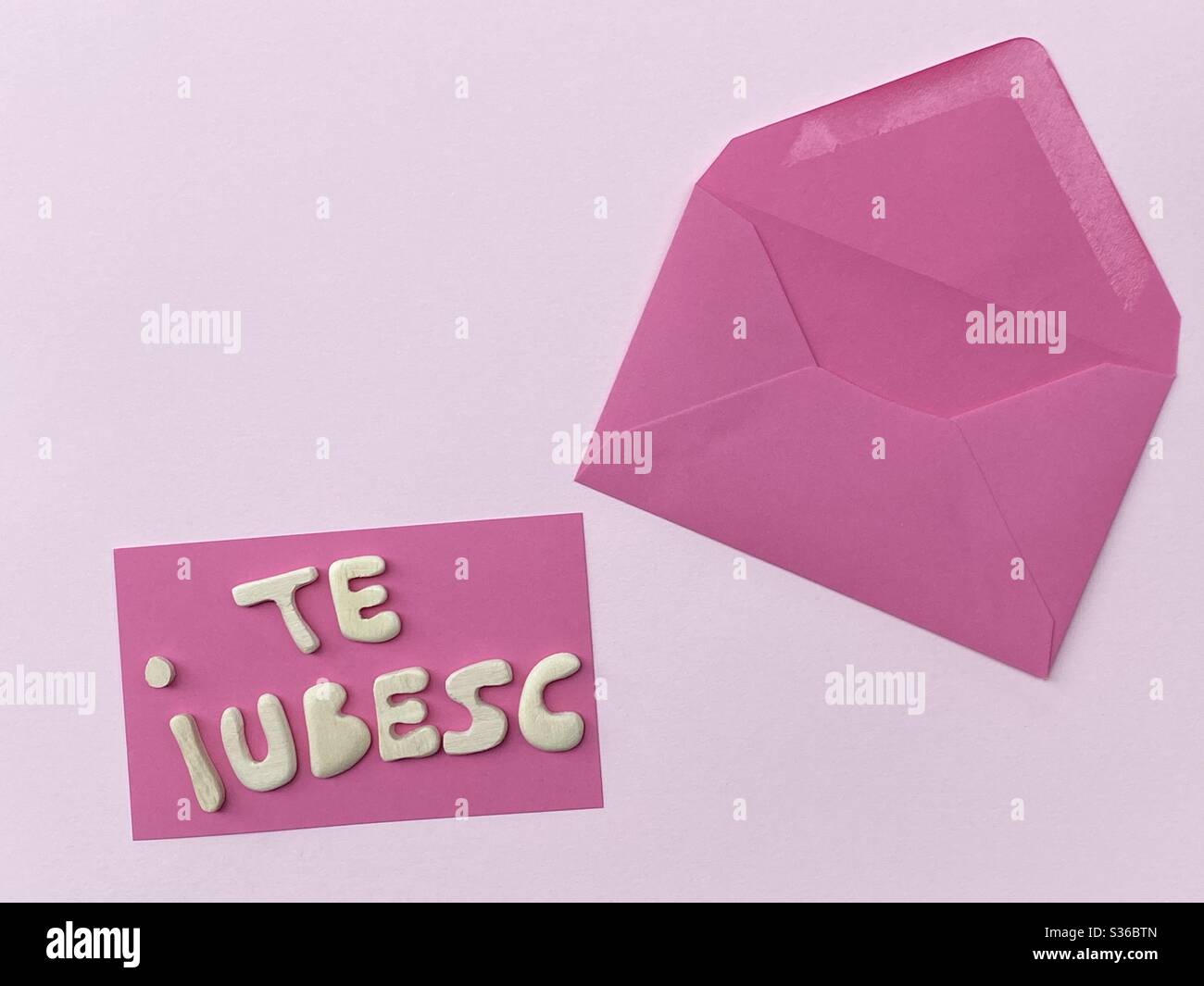 Te iubesc, romanian text meaning I love you composed with handmade wooden letters over pink card Stock Photo