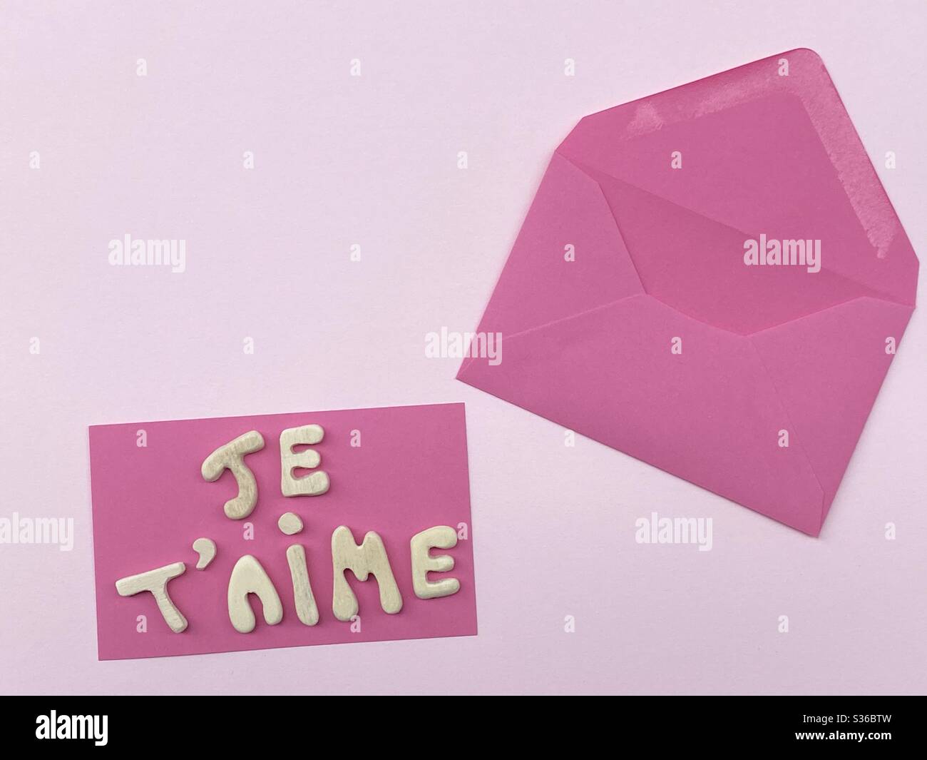 Je t’aime, french text meaning I love you composed with handmade wooden letters over pink color Stock Photo