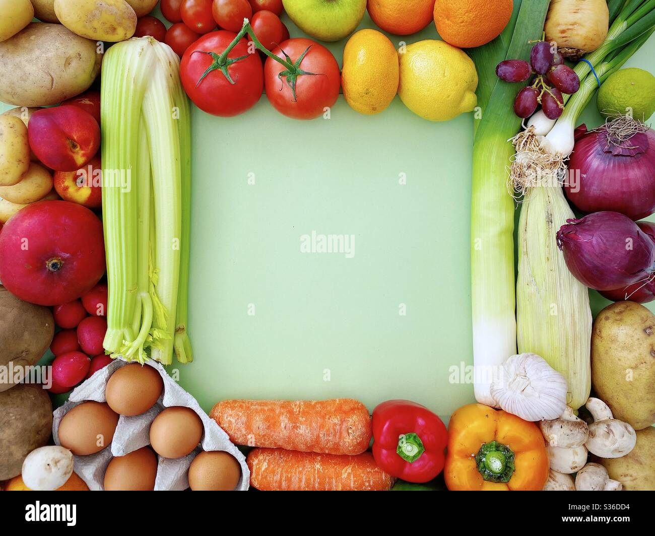 Vibrant and colorful fruit and vegetables create a square frame with copy space against a pastel green background. Fresh and organic food from a local farmers market. - Smartphone Captured Stock Image