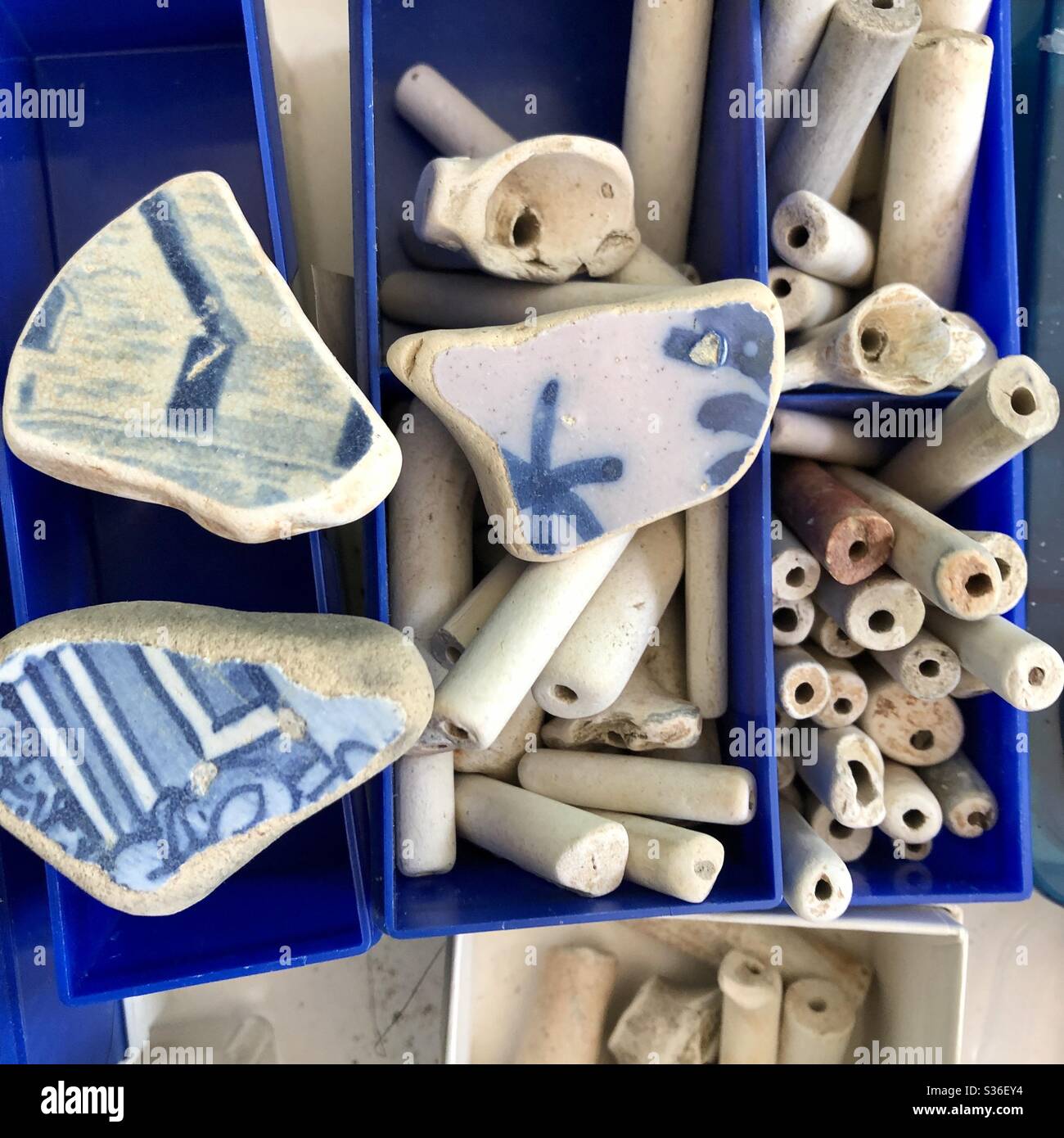 Mudlarking finds of Delft pottery shards and pipe stems from Thames River London England being sorted for crafting Stock Photo