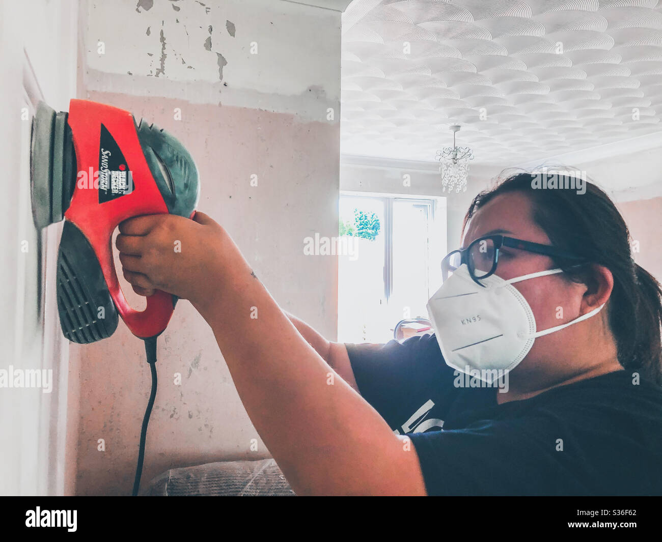 A lady sanding a door with an electric sander. - Smartphone Captured Stock Image