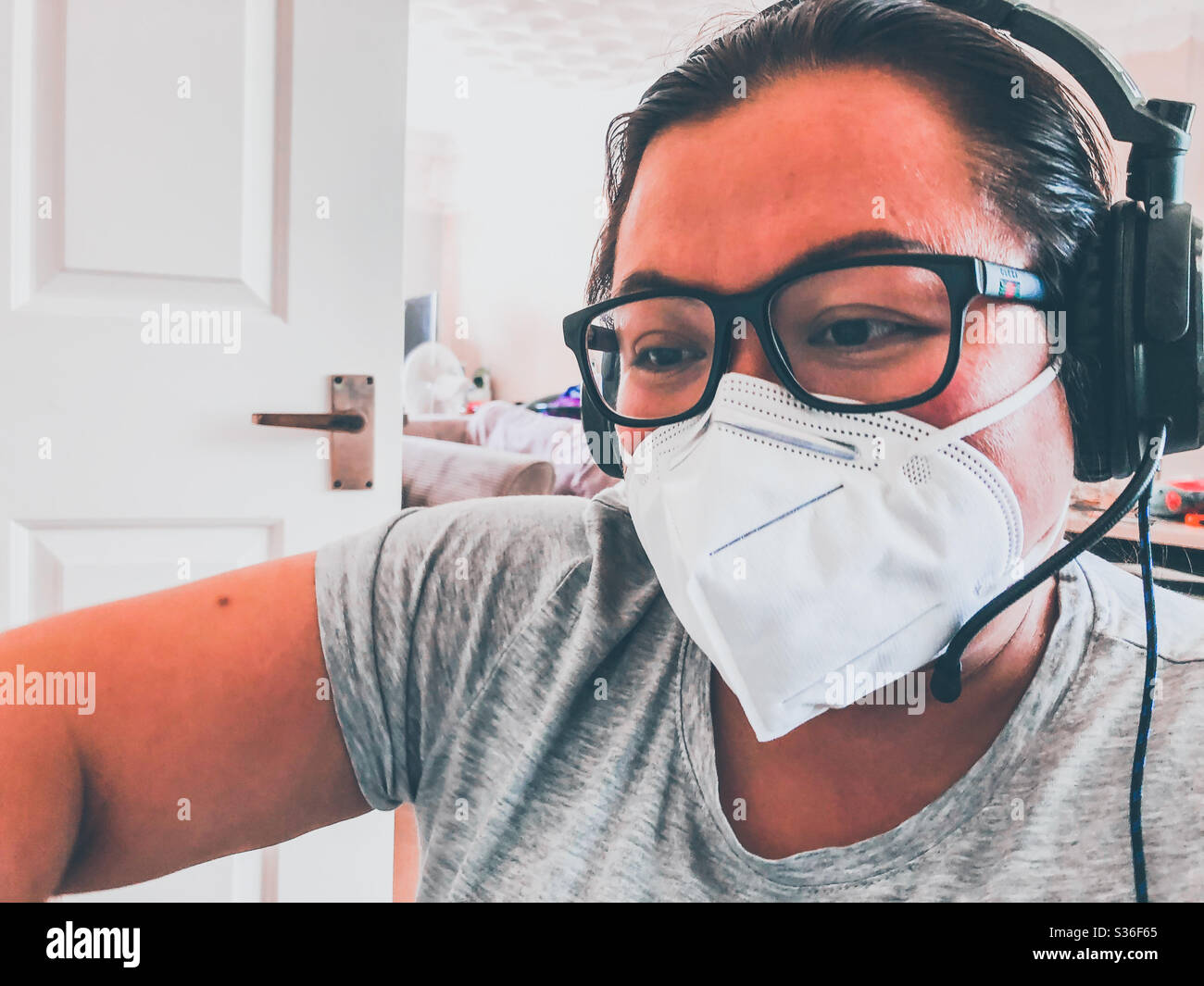 Lady wearing a face mask to protect against inhaling dust glasses and a set of computer headphones as ear defenders Stock Photo Alamy