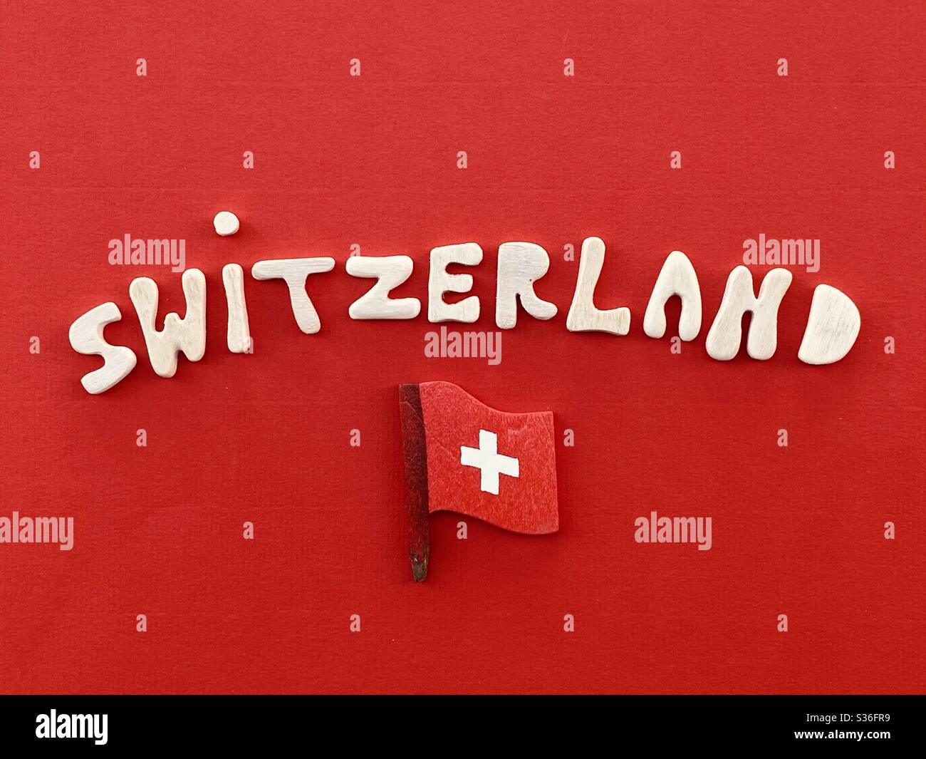 Switzerland, souvenir composed with handmade wooden letters over red color and national flag - Smartphone Captured Stock Image