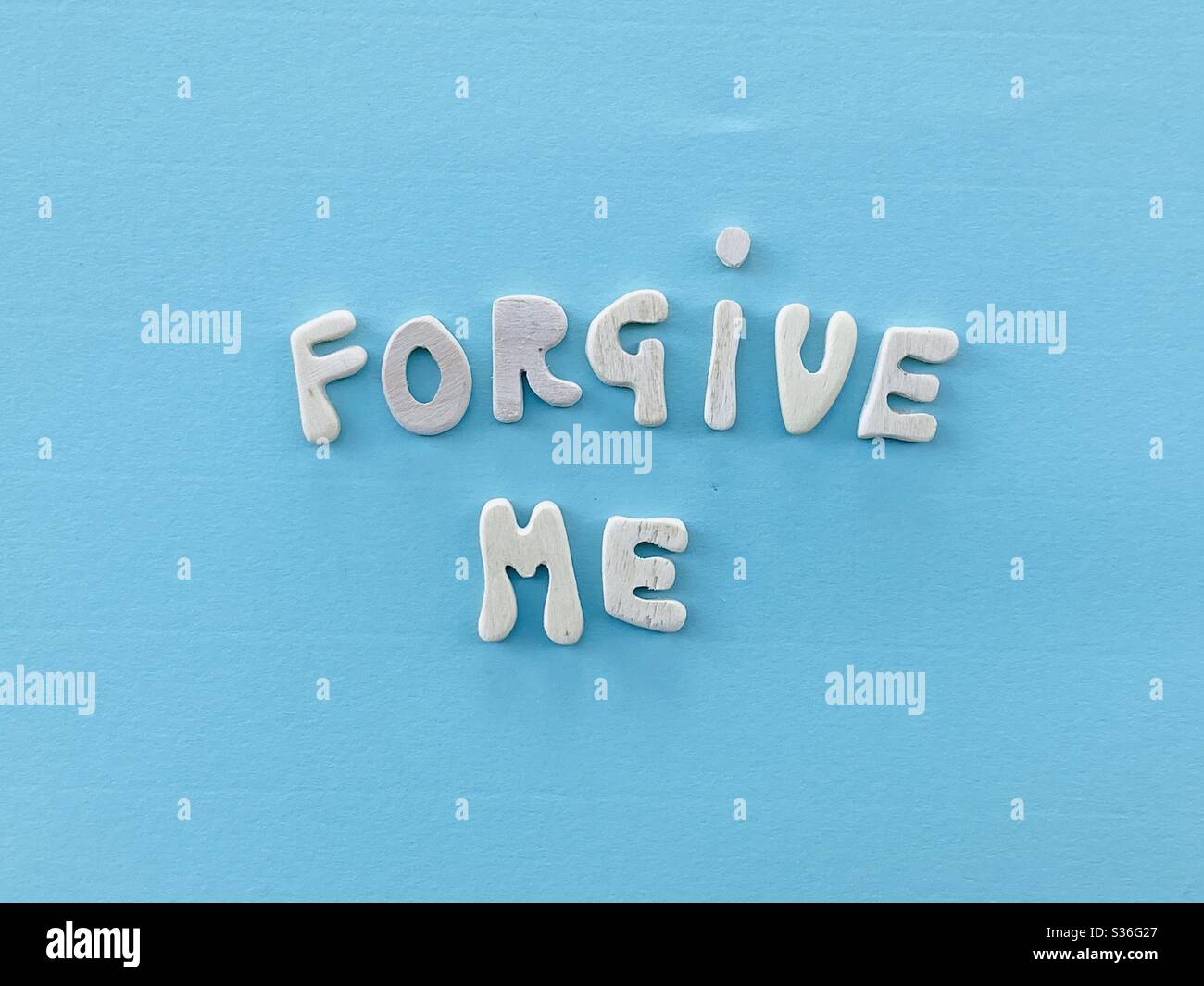 Forgive me message composed with handmade wooden letters over blue color - Smartphone Captured Stock Image