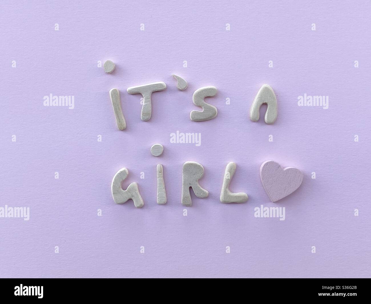 It’s a girl message with a pink wooden heart composed with handmade wooden letters over pink background Stock Photo
