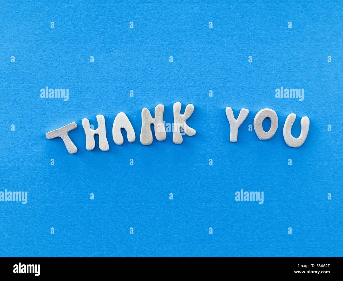 Thank you text composed with handmade wooden letters over blue color - Smartphone Captured Stock Image