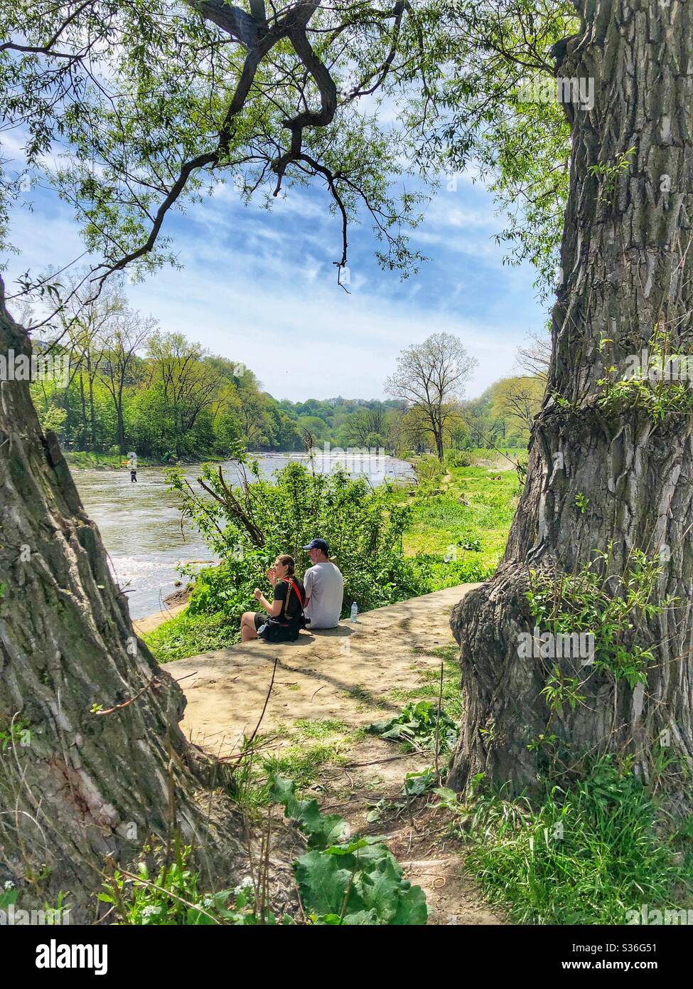 A couple enjoying a sunny spring day by the river. - Smartphone Captured Stock Image
