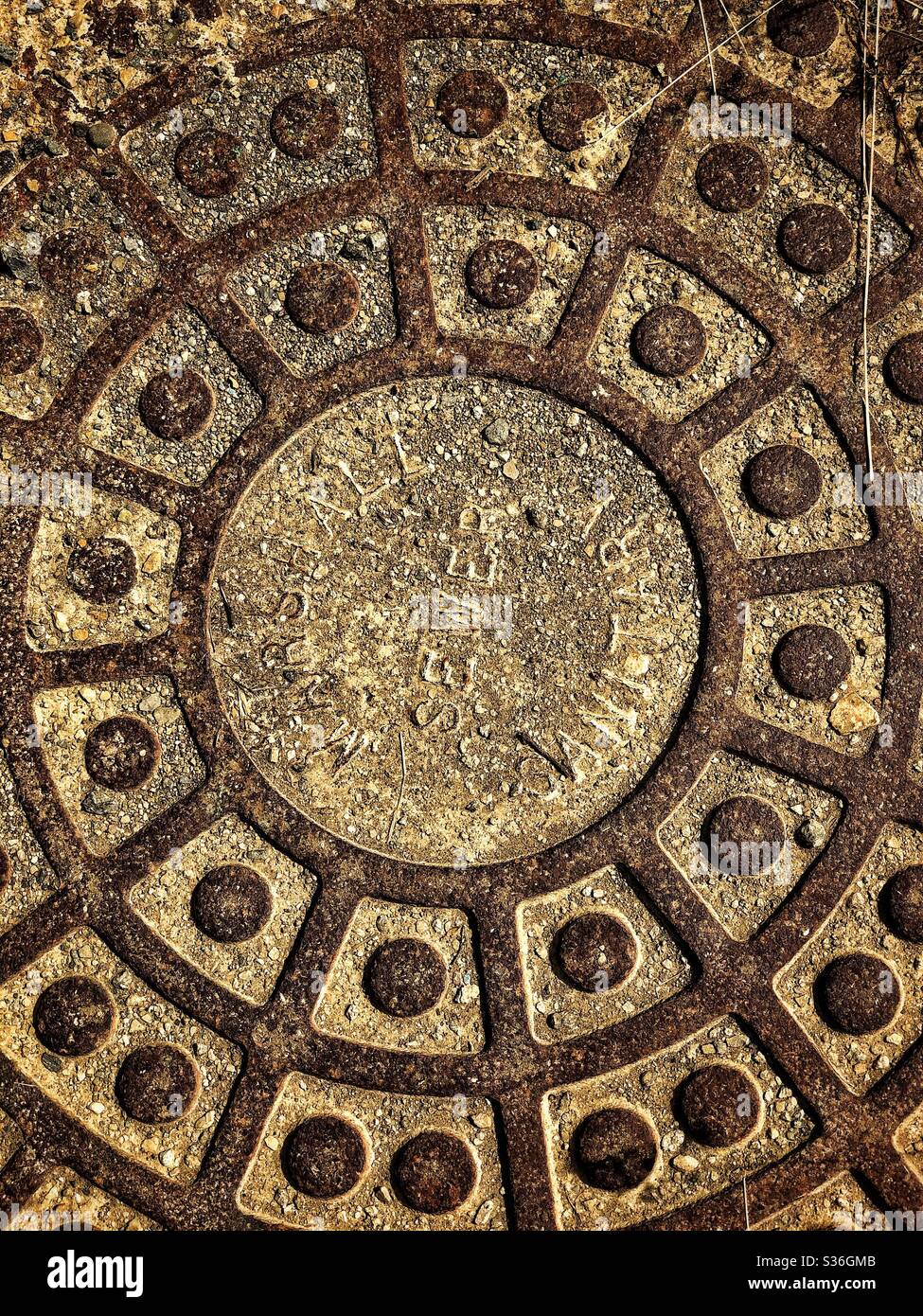 An overhead view of a manhole cover with circular patterns - Smartphone Captured Stock Image