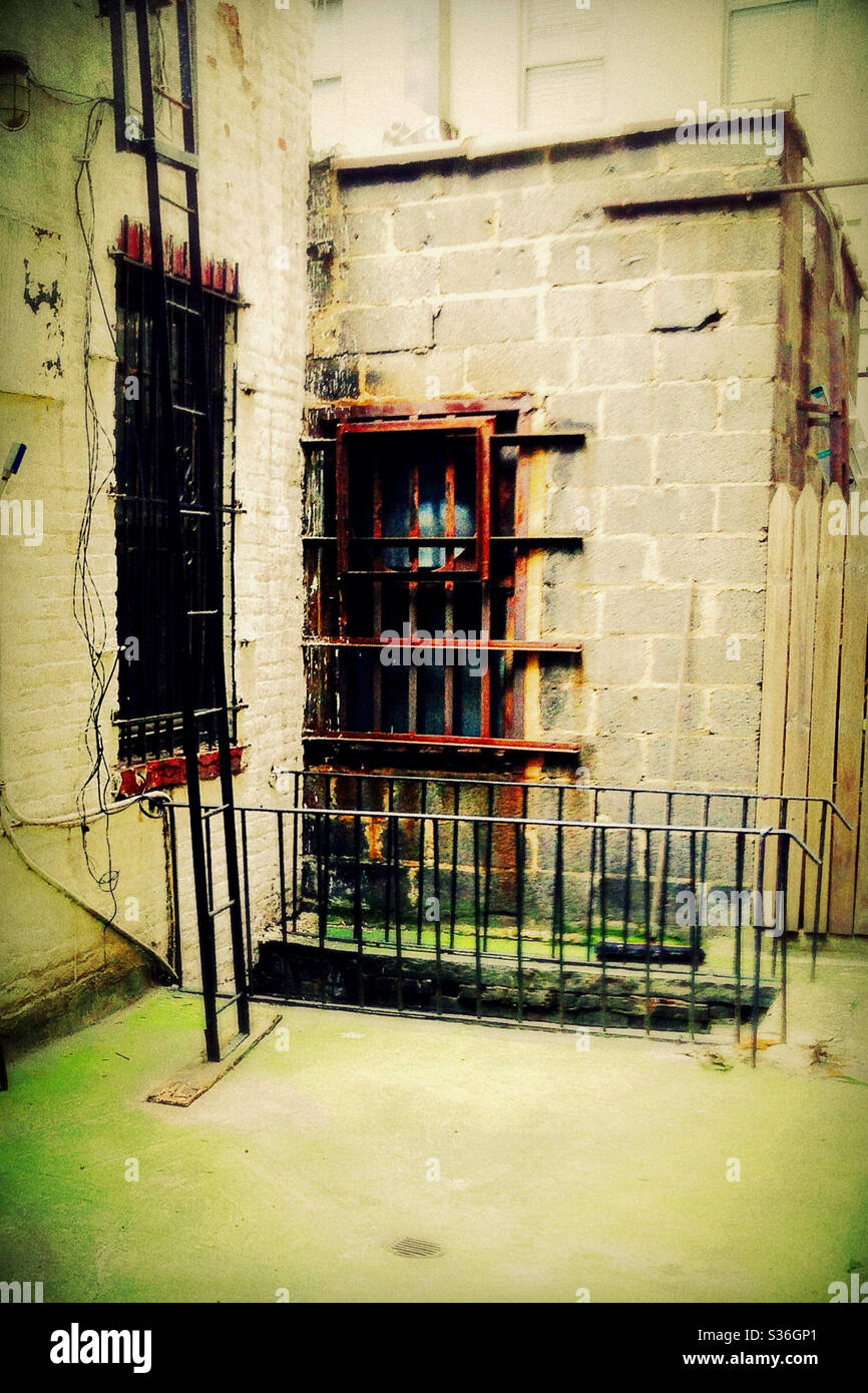 Scary Back Alley with Rusted Bars on Windows with Fire Escape Stock Photo