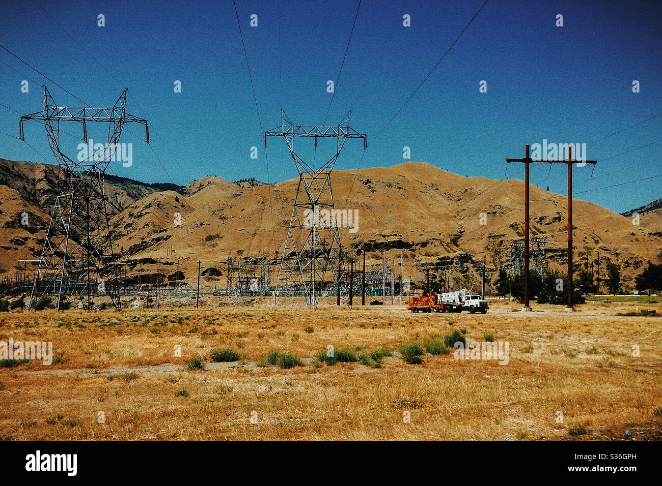 Power Lines, Towers, and Service Trucks along a Hillside Stock Photo