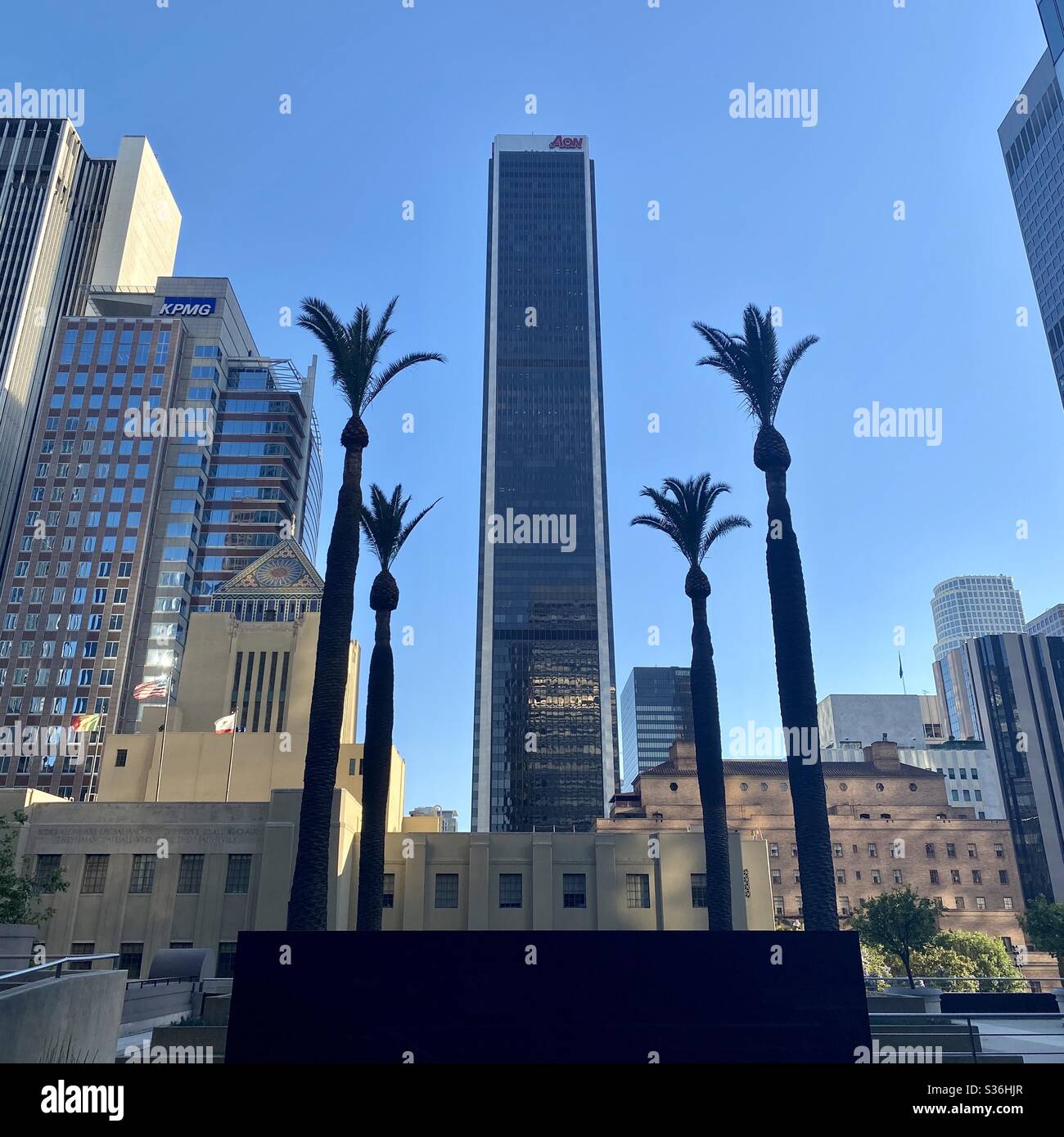 LOS ANGELES, CA, MAY 2020: silhouetted palm trees frame AON Tower skyscraper in Downtown, with LA Public Library Central Branch in foreground Stock Photo