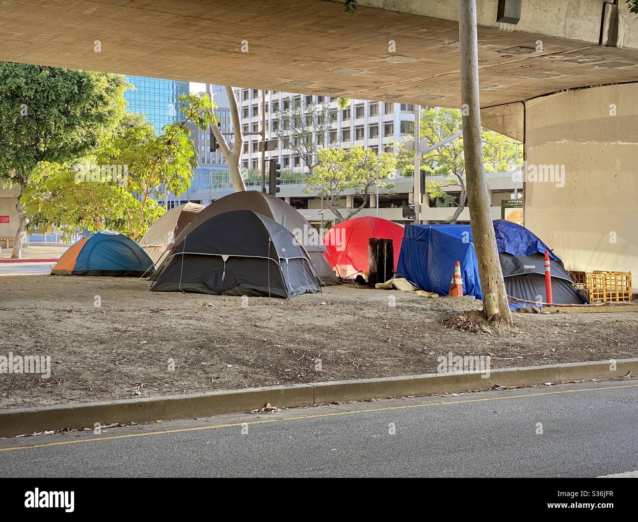 LOS ANGELES, CA, MAY 2020: close view homeless encampment including several tents, near office buildings, apartments and hotels, under an overpass in Downtown. - Smartphone Captured Stock Image