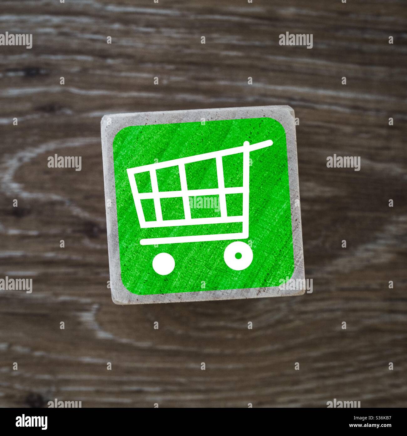 A shopping trolley or cart sign, symbol or icon on a wooden block and background denoting retail stores with copy space - Smartphone Captured Stock Image