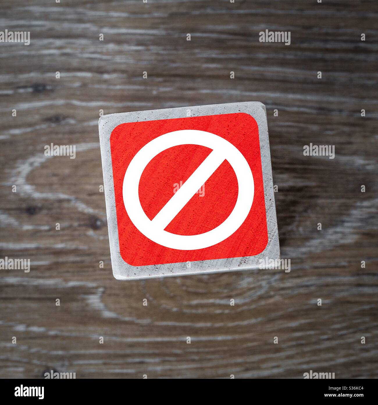 A red stop sign or forbidden icon on a wooden block and a wooden background with copy space - Smartphone Captured Stock Image