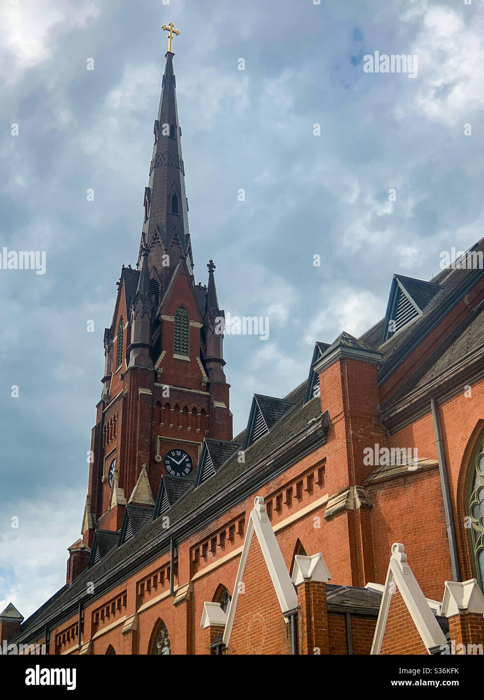 DUBUQUE, IOWA, May 26, 2020--Landscape photo of the steeple of an old red brick historic church with symmetrical windows and peaks on a sunny spring day. Stock Photo