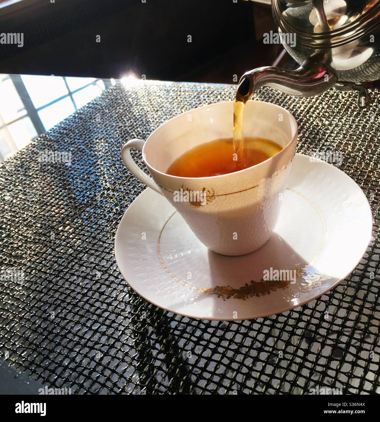Hot tea being poured into a Rosenthal china cup during a high tea service - Smartphone Captured Stock Image