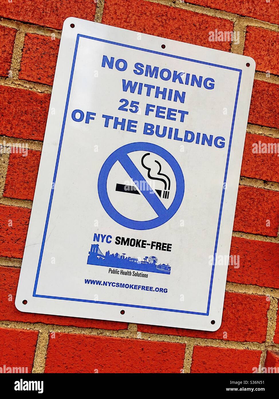 Smoke free New York City sign with universal prohibition symbol plastered on a brick wall, New York city, USA - Smartphone Captured Stock Image