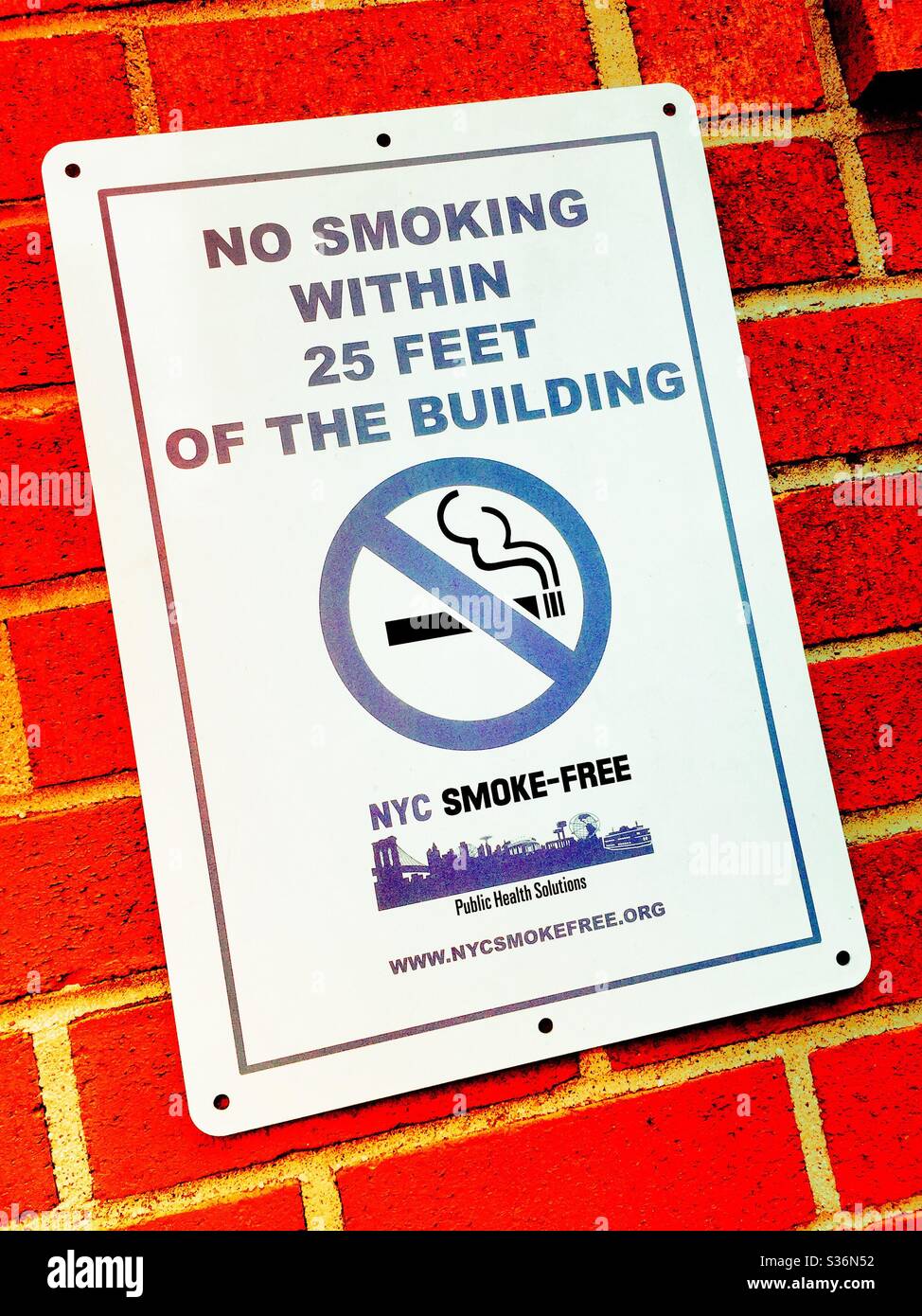 NYC smoke-free sign with the universal no symbol plastered on a brick wall, New York City, USA - Smartphone Captured Stock Image