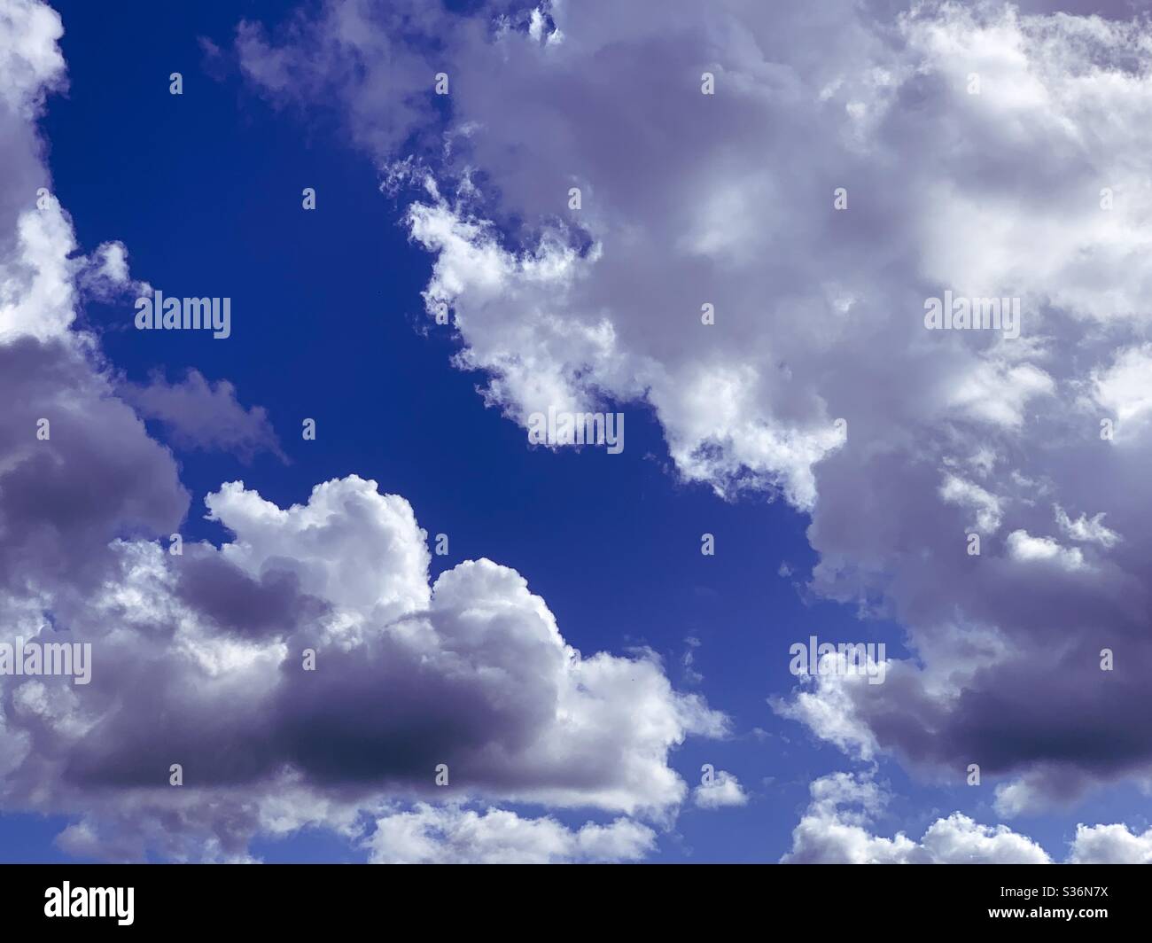 blue sky breaking through the white cumulus  clouds to reveal blue sky - Smartphone Captured Stock Image