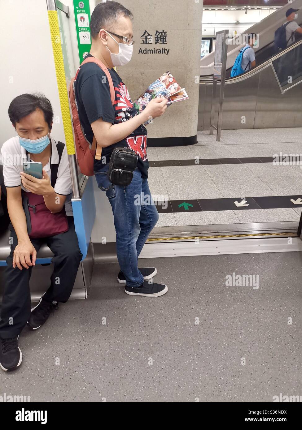 Reading anima magazine on the MTR in Hong Kong. Stock Photo