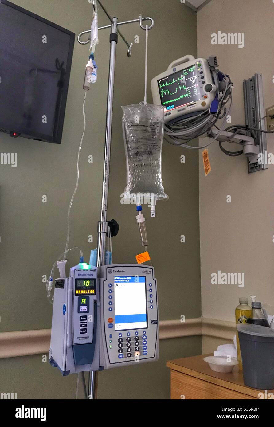 In the hospital: IV pole, infusion and fluids bags, cardiovascular telemetry monitor Stock Photo