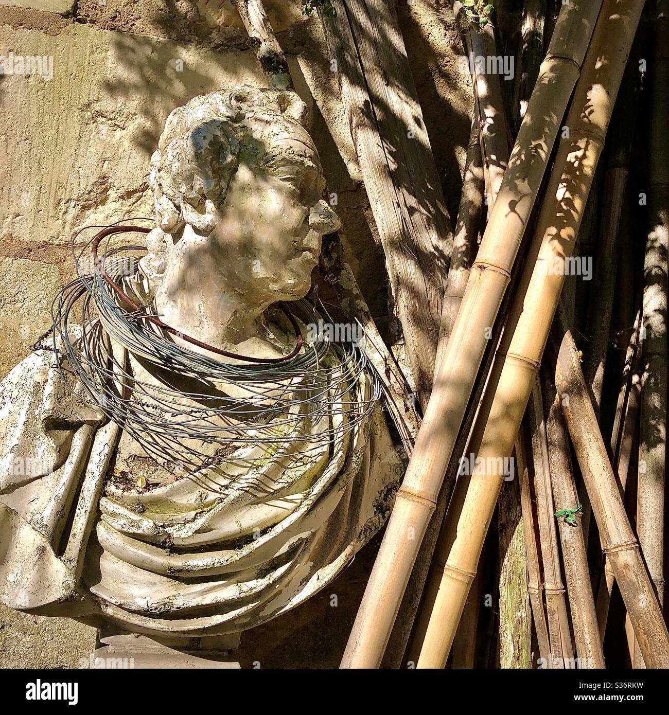 Old plaster bust of Roman emperor in corner of French garden. Stock Photo
