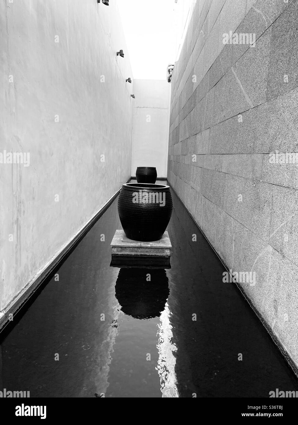 Huge decorative pots placed between two walls. Black and white art piece - Smartphone Captured Stock Image