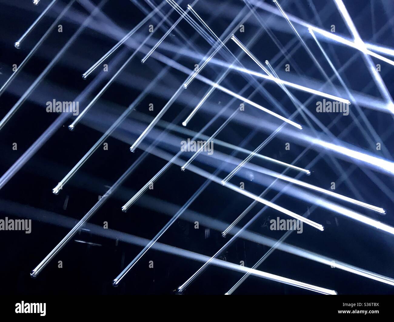 Crossing lights creating a vivid pattern with a dark background on event stage - Smartphone Captured Stock Image