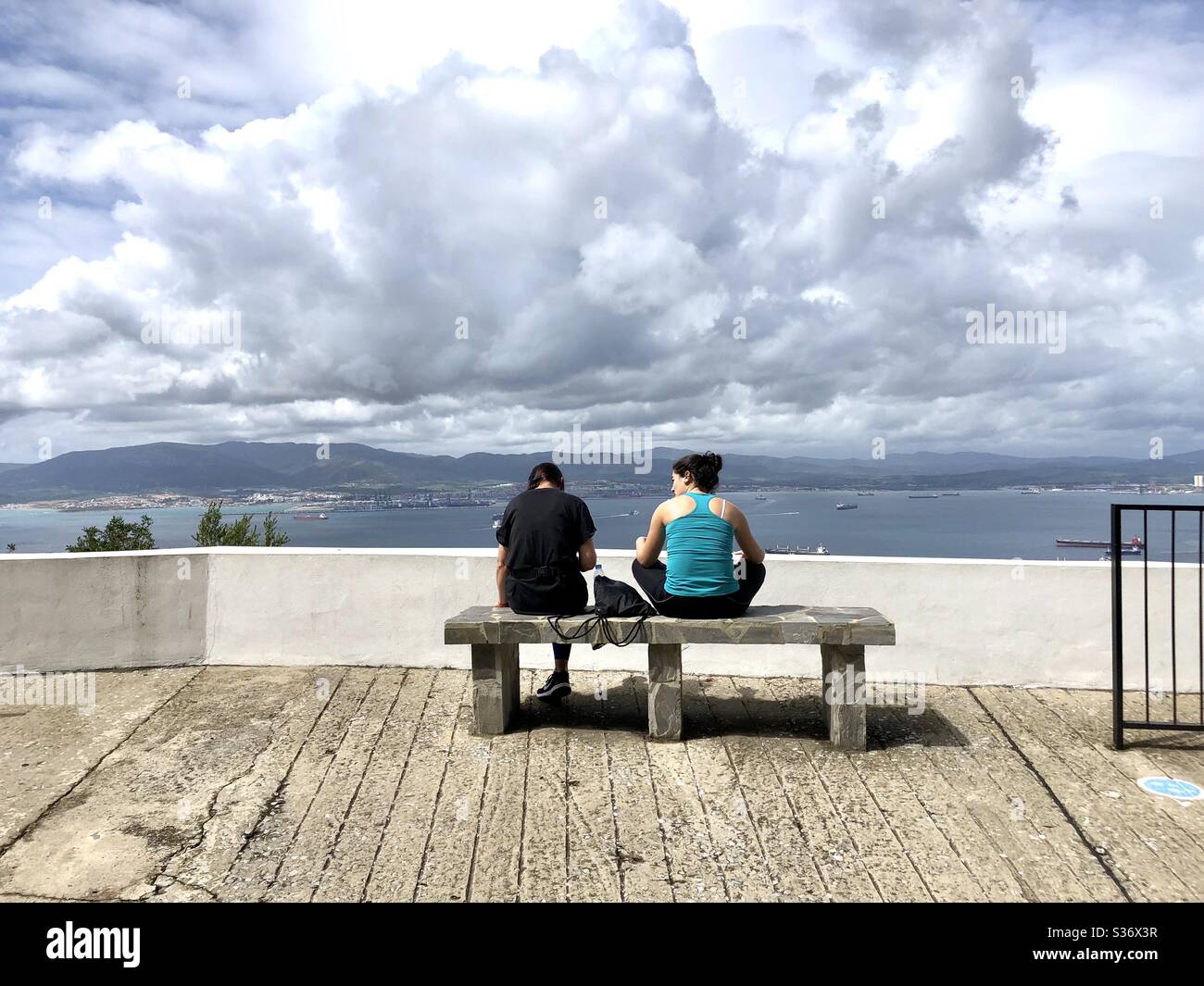 Two women sitting on a bench overlooking the bay of Gibraltar - Smartphone Captured Stock Image
