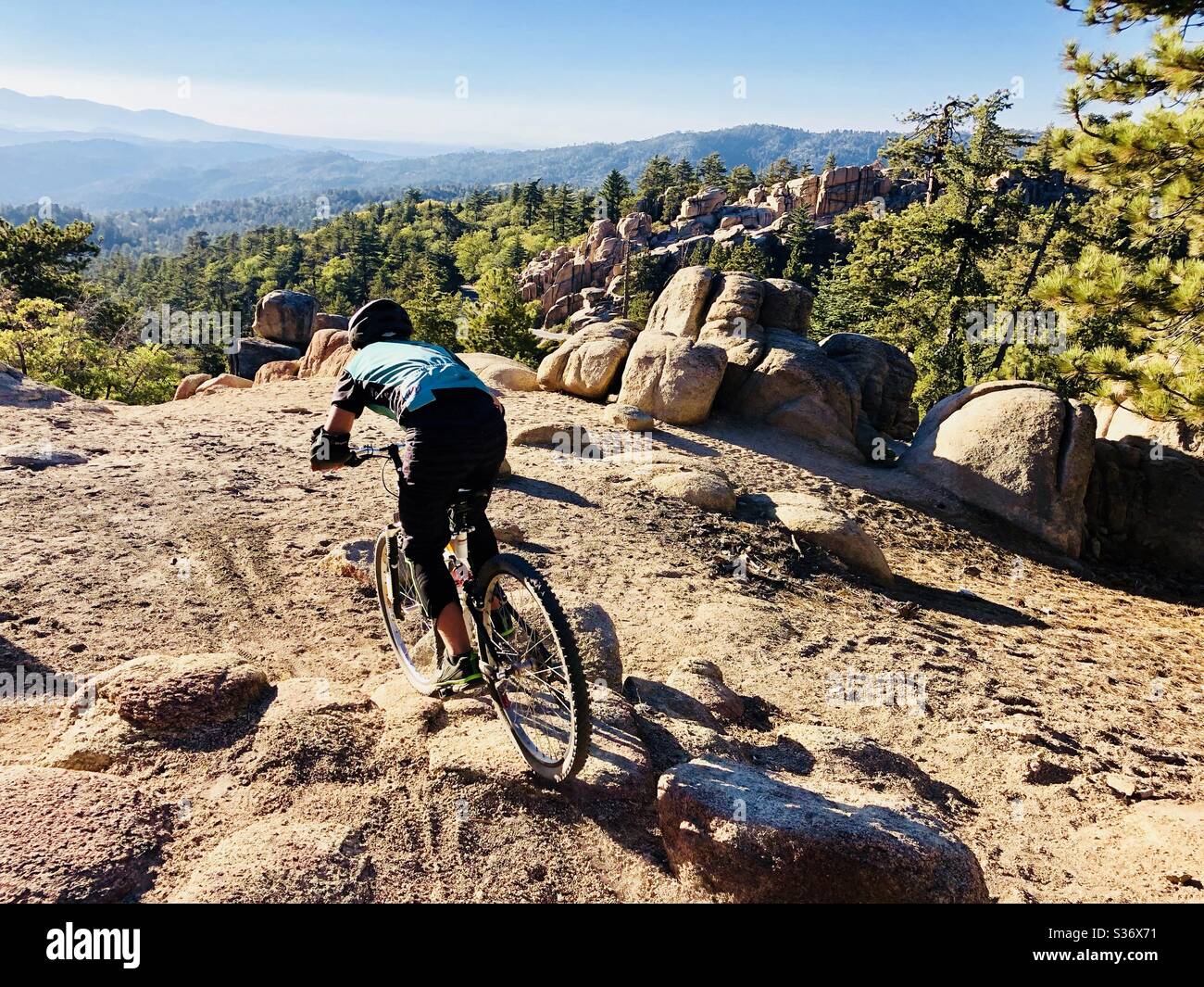 A young man riding his mountain bike with a gorgeous scenic overview. Stock Photo
