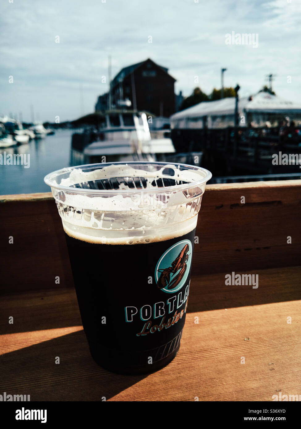 waterfront on Portland's bustling Commercial Street: Outside bar at the Portland Lobster Company a glass of Allagash Black Locally crafted MAINE beer. Stock Photo