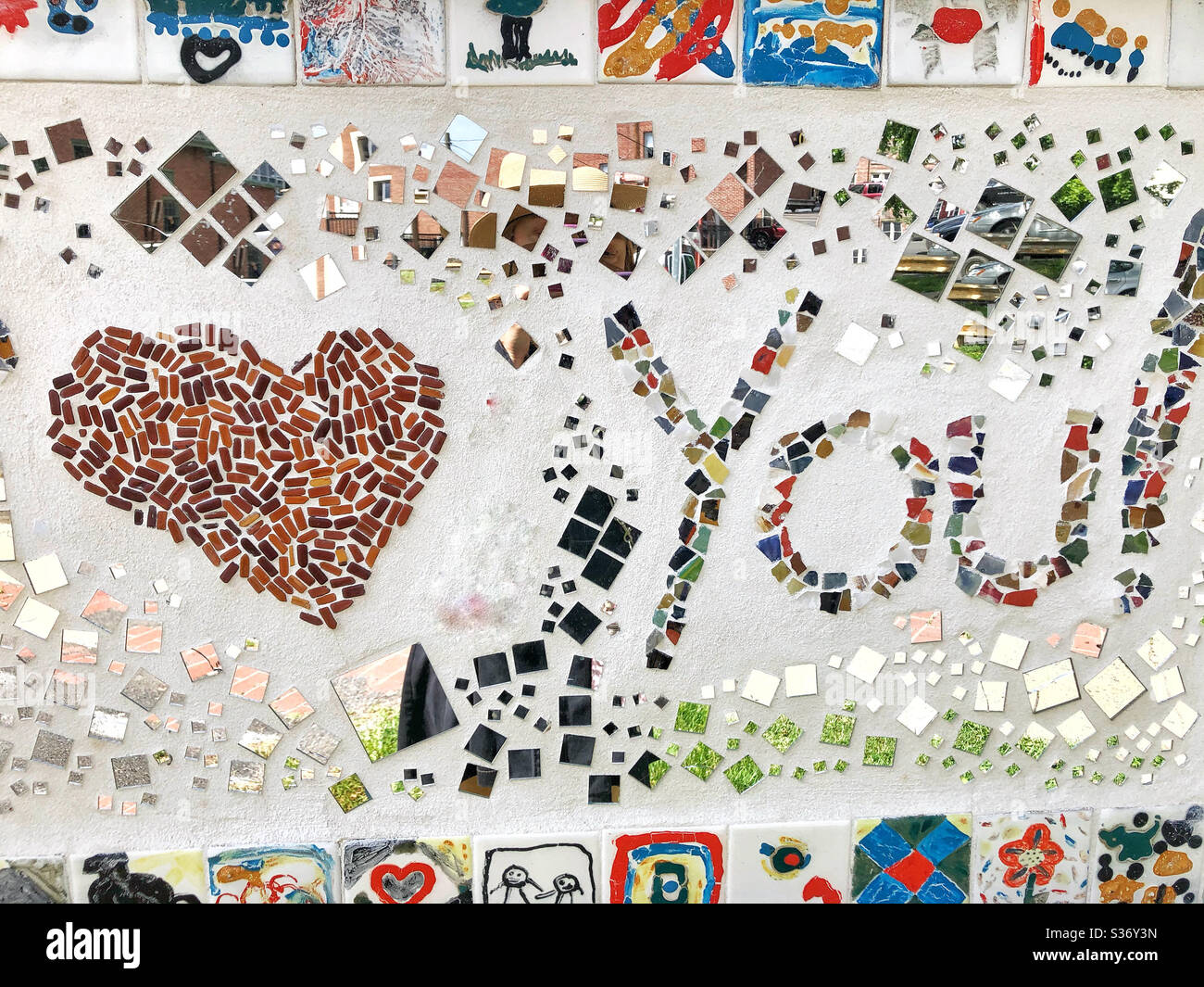 Mural made by children with broken plates, tile, and mirrors that has a heart to represent love You - Smartphone Captured Stock Image