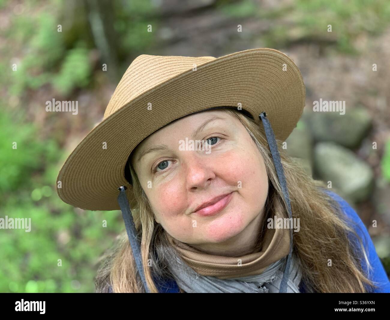 Portrait Woman looking at camera hiking with new hat - Smartphone Captured Stock Image