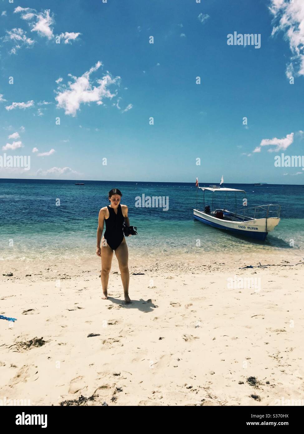 Woman walking on exotic beach in swimsuit with snorkel gear. San Juan, Siquijor, Philippines