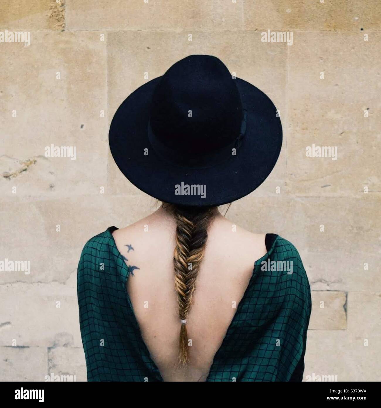 Back of a woman with fish braid hair wearing a hat. Stock Photo