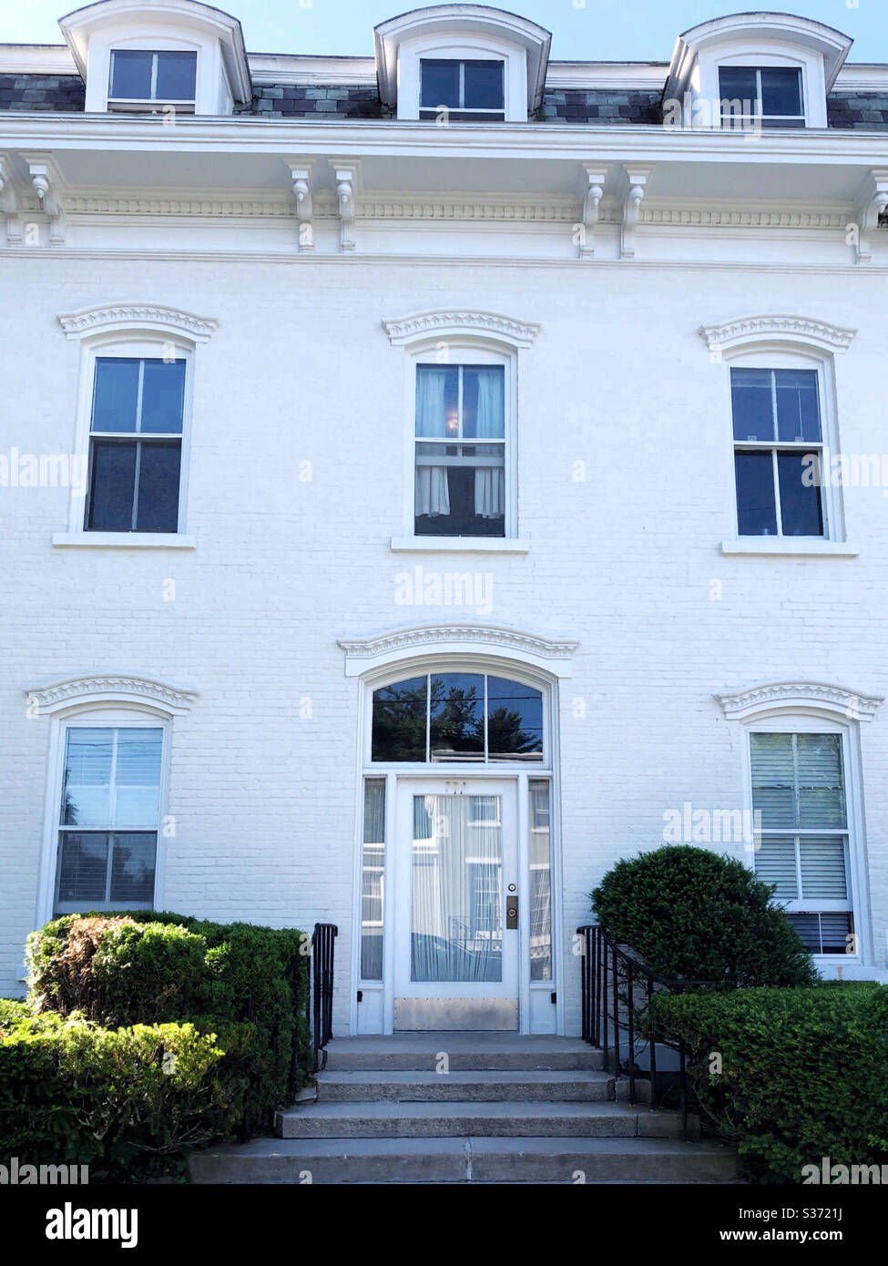 Pretty white house with nicely trimmed shrubbery at entrance - Smartphone Captured Stock Image
