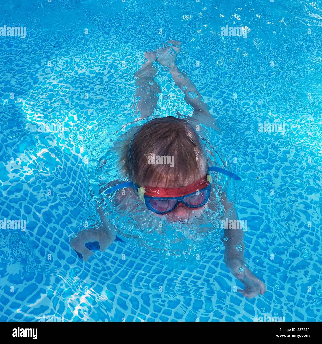 Boy swimming in a paddling pool wearing goggles. Stock Photo