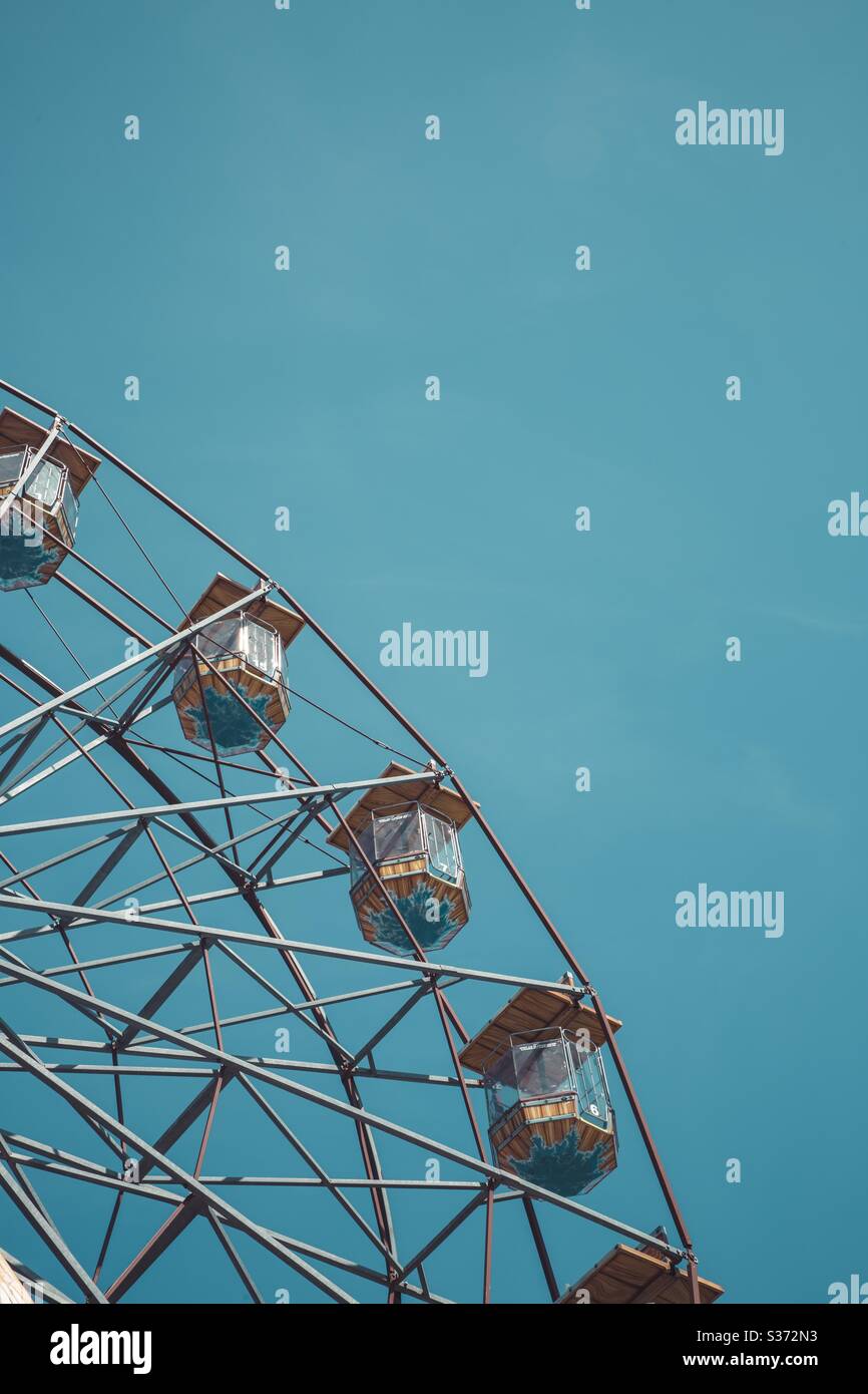 A close-up of the seats and chairs on a ferris wheel or big wheel at a fairground or funfair with a clear blue sky and copy space on a vertical composition - Smartphone Captured Stock Image