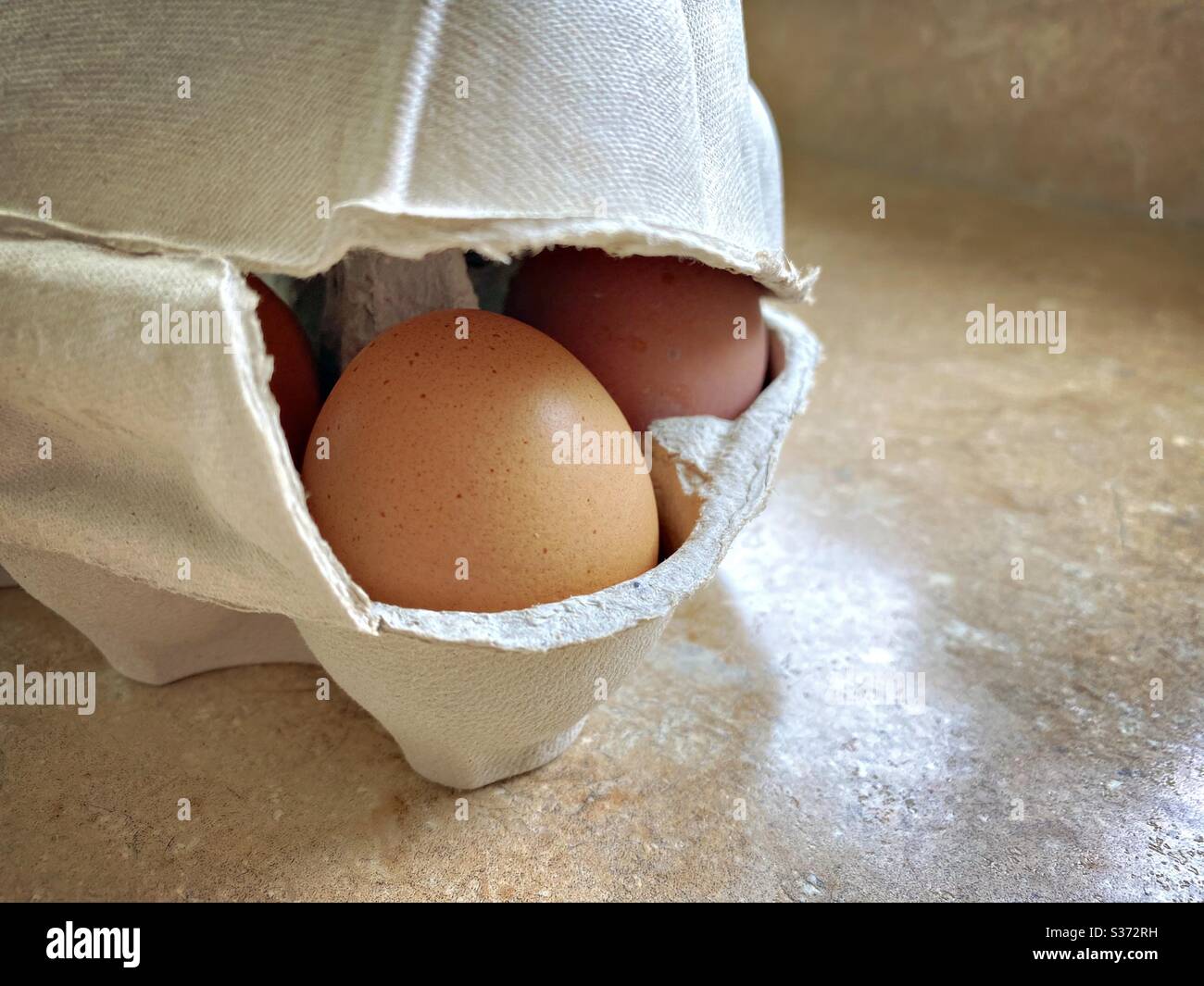 Closeup view of free range organic farm eggs in a traditional recyclable cardboard carton. Egg box details. Tray of six eggs. Half a dozen on the kitchen counter - Smartphone Captured Stock Image