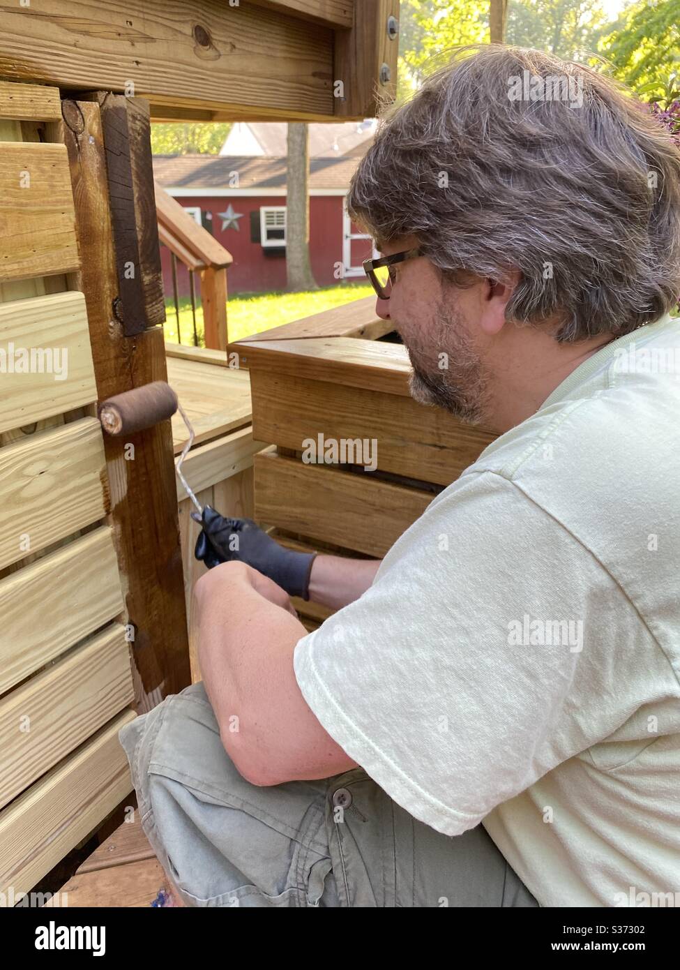 One man staining deck boards with roller Stock Photo Alamy