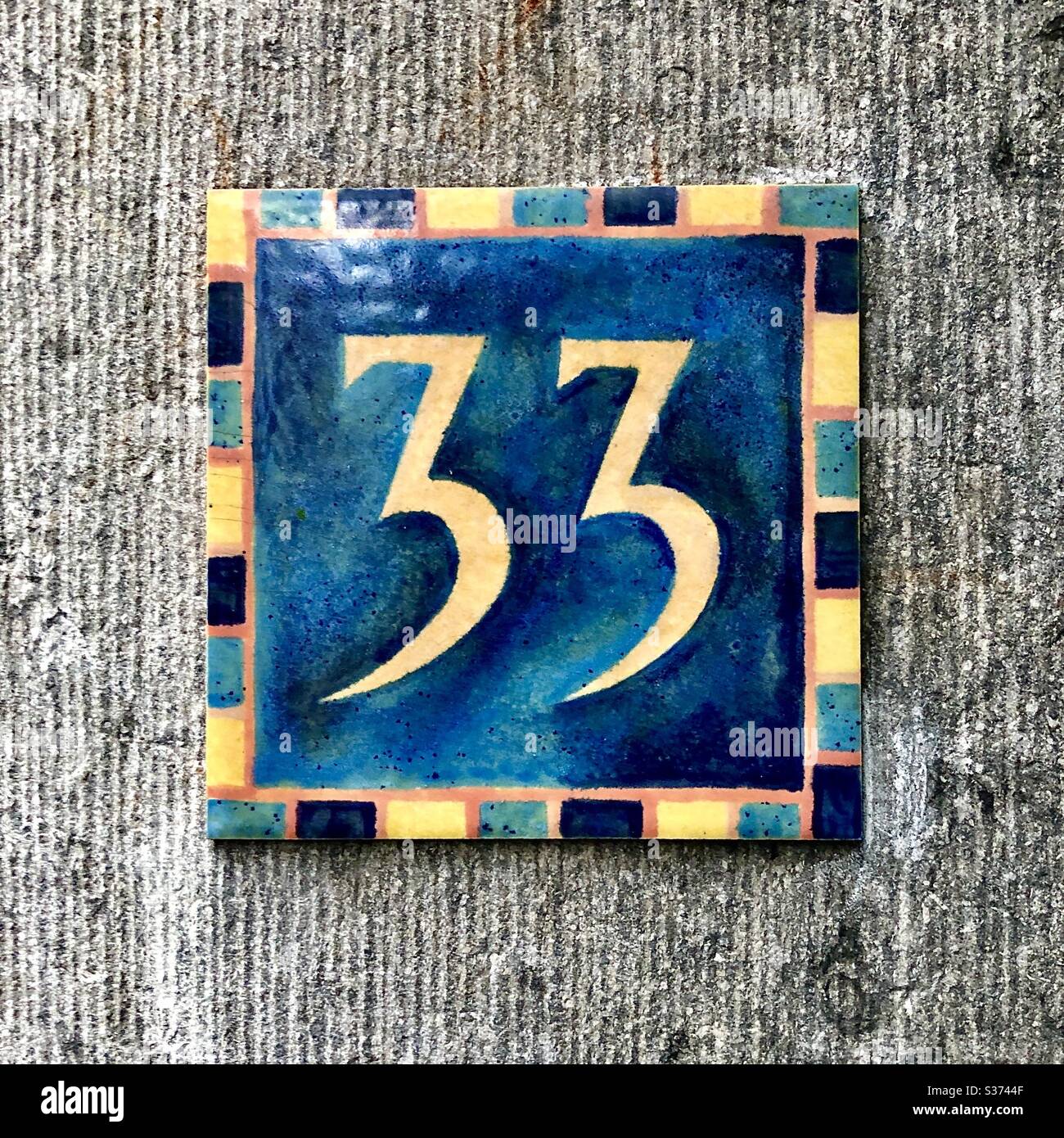 Hand-made ceramic tile “33” house number on street in Brussels, Belgium. Stock Photo