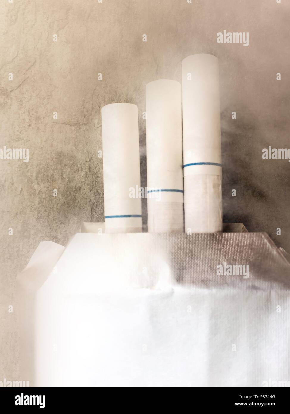 Up in smoke. Three white filter cigarettes stick out of a pack. Symbolic three strikes. - Smartphone Captured Stock Image