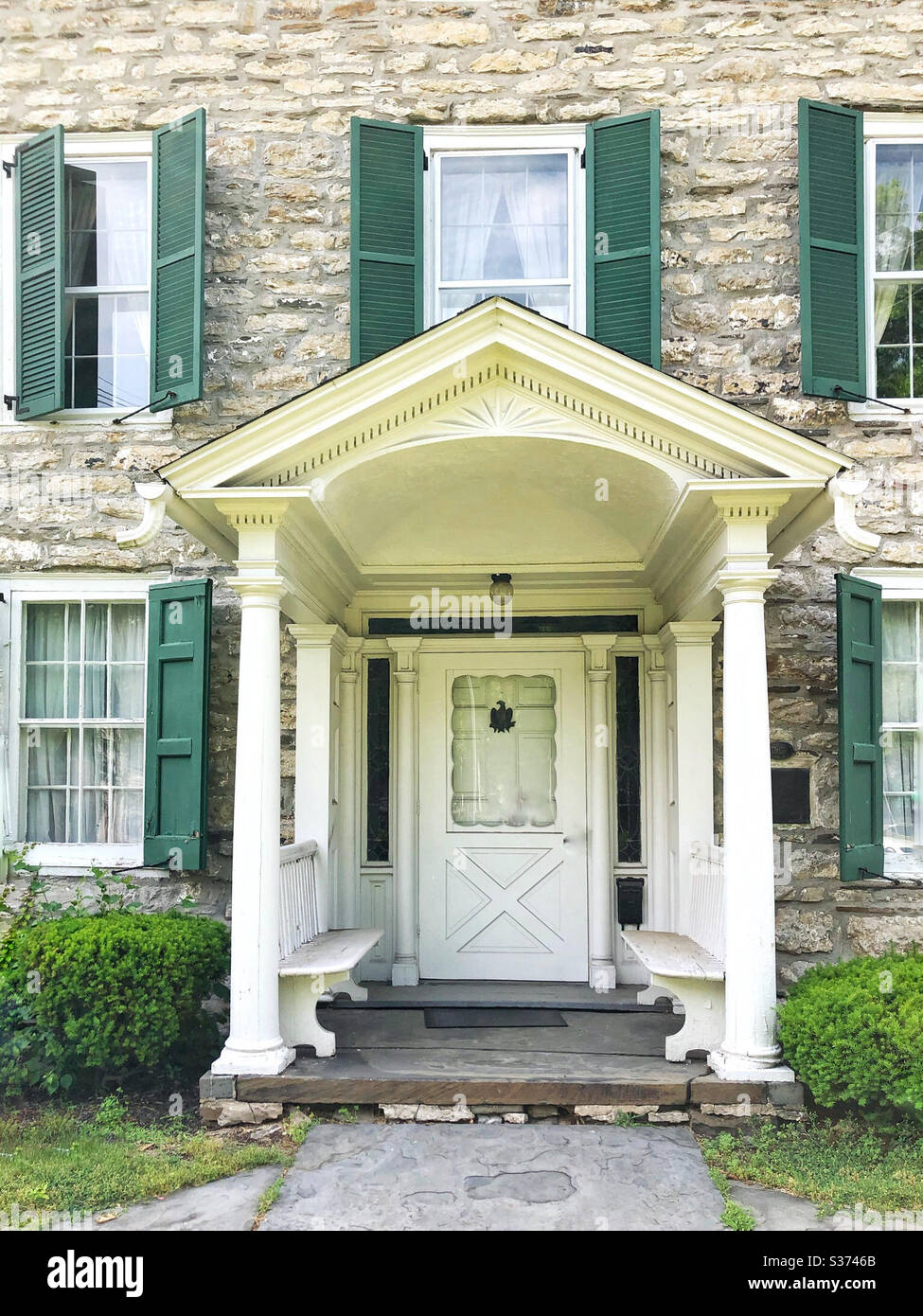 Front door of stone house with green shutters Stock Photo