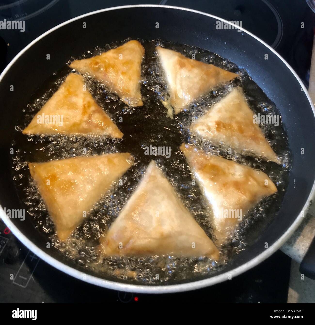 Nicely browning samosas in the frying pan Stock Photo