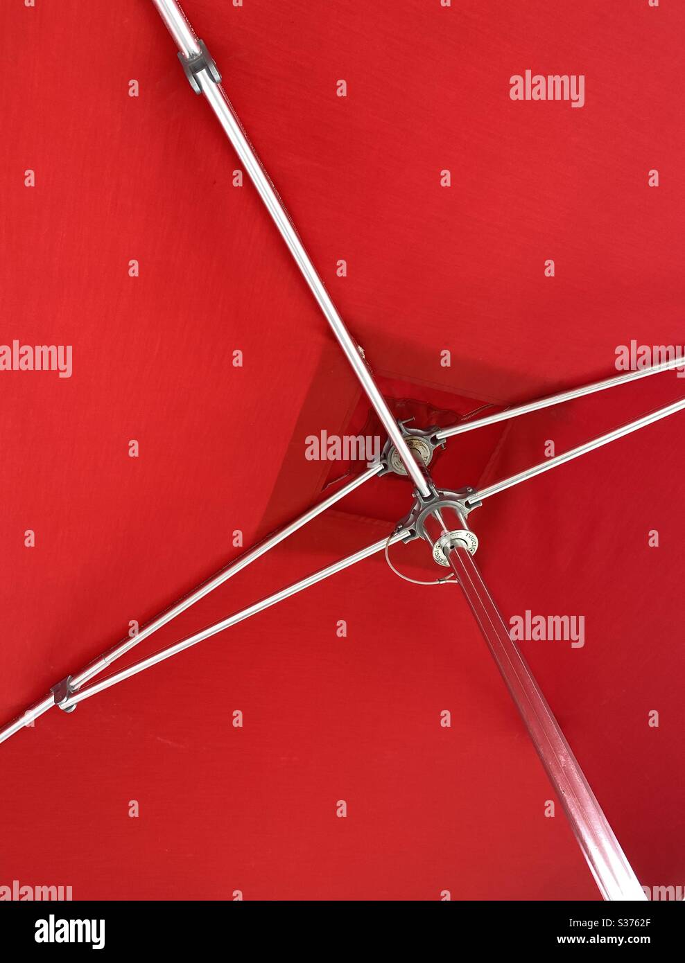 Underside of a bright red outdoor umbrella with silver steel pole Stock Photo