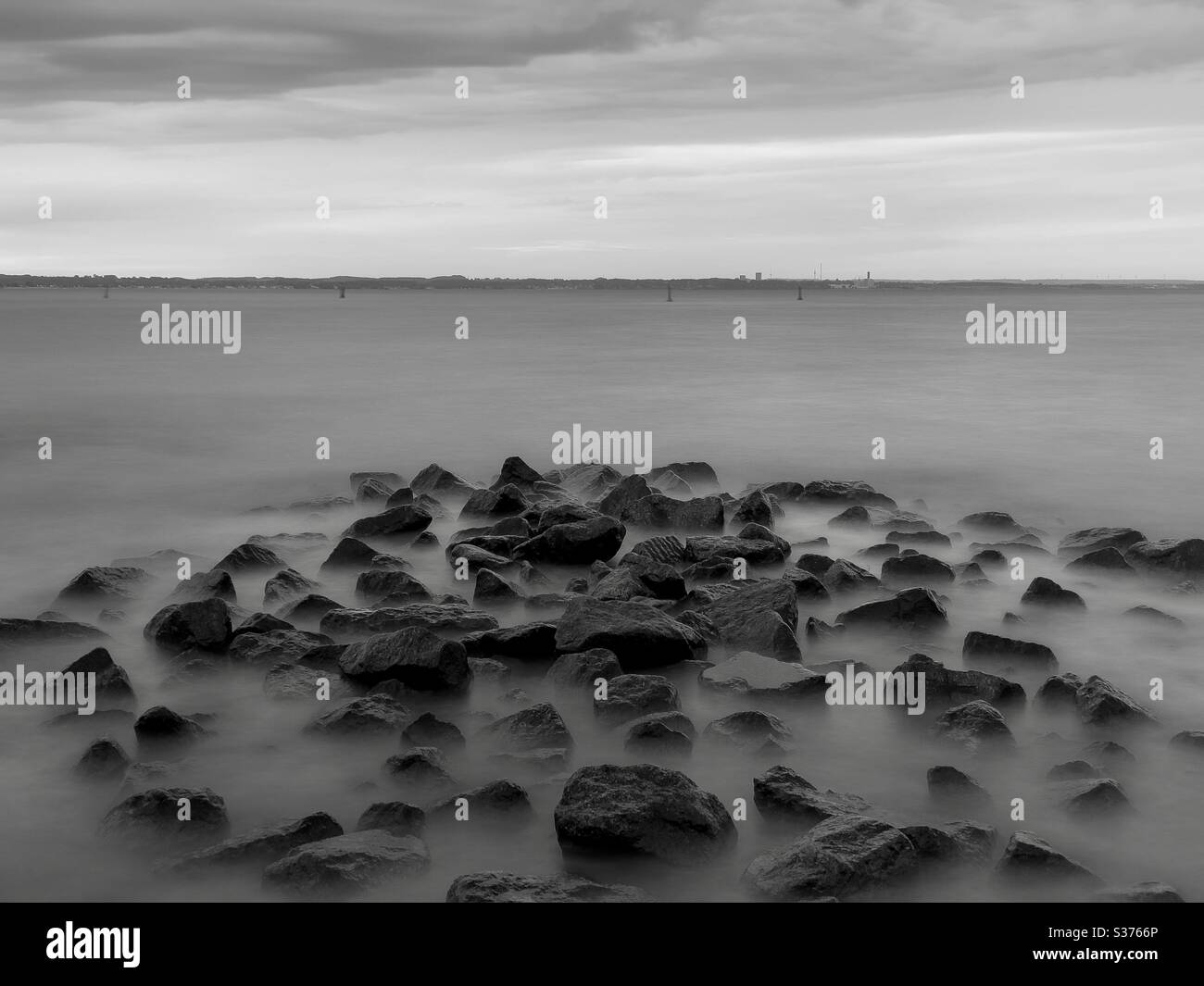 Black and white long exposure of sea waves with the stones in foreground - Smartphone Captured Stock Image Black and white long exposure of sea waves with the stones in foreground - Smartphone Captured Stock Image