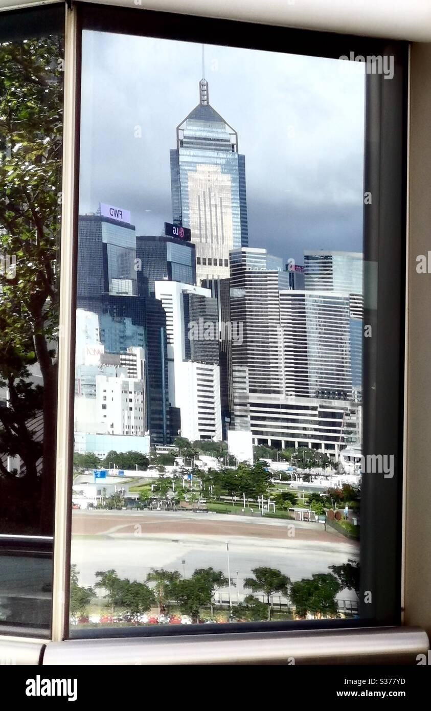 The Wan Chai tower reflected on the glass window ms of the IFC tower in Hong Kong. - Smartphone Captured Stock Image