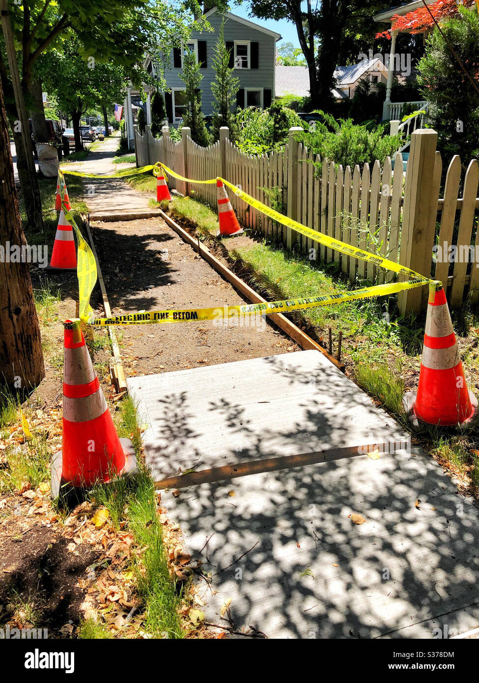 Construction site for building a cement or concrete sidewalk. Site has been leveled, wood frame installed, and has been checked for underground electric wires. Marked with yellow safety tape, cones - Smartphone Captured Stock Image
