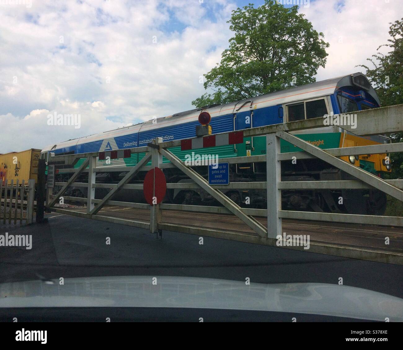 View from through the car windscreen of a Freight train passing over a rural level crossing, UK - Smartphone Captured Stock Image