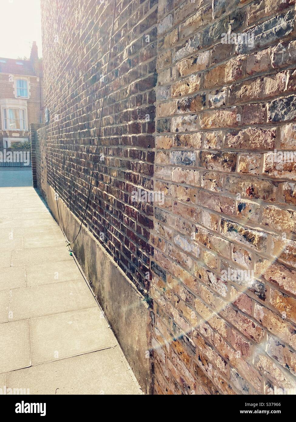 Brick wall and pavement in a Victorian terraced street of Stoke Newington, north London, UK - Smartphone Captured Stock Image